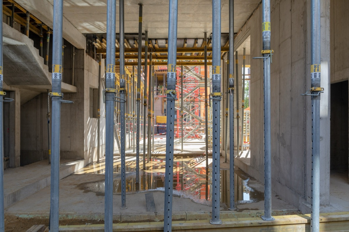 Estructura de concreto en obra, con puntales metálicos bajo la losa recién colada.