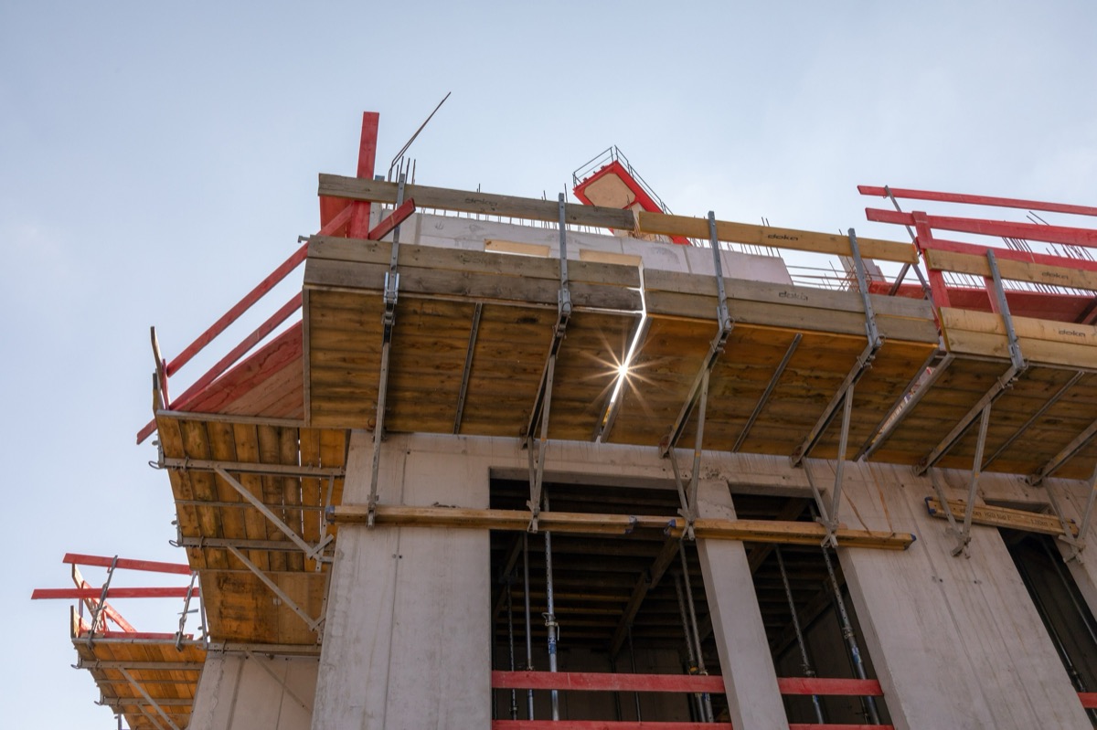 Borde de una losa en obra con cimbra de madera, barandas de seguridad y columnas de concreto.